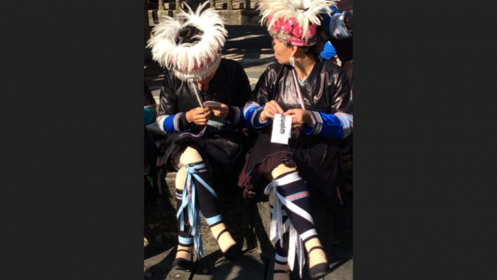 Dong dancers dressed for tourists embroidering shoe soles which are a very common hobby